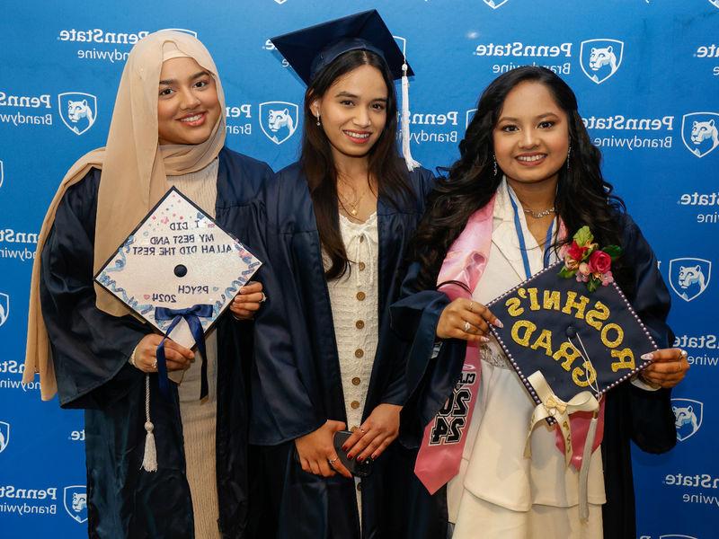 三名女学生穿着毕业礼服摆姿势拍照.