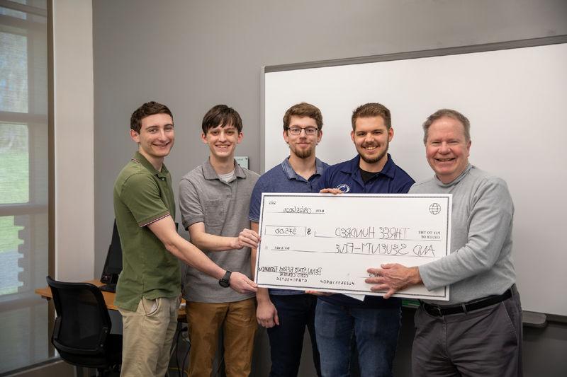 Group of male students pose for photo with $375 check