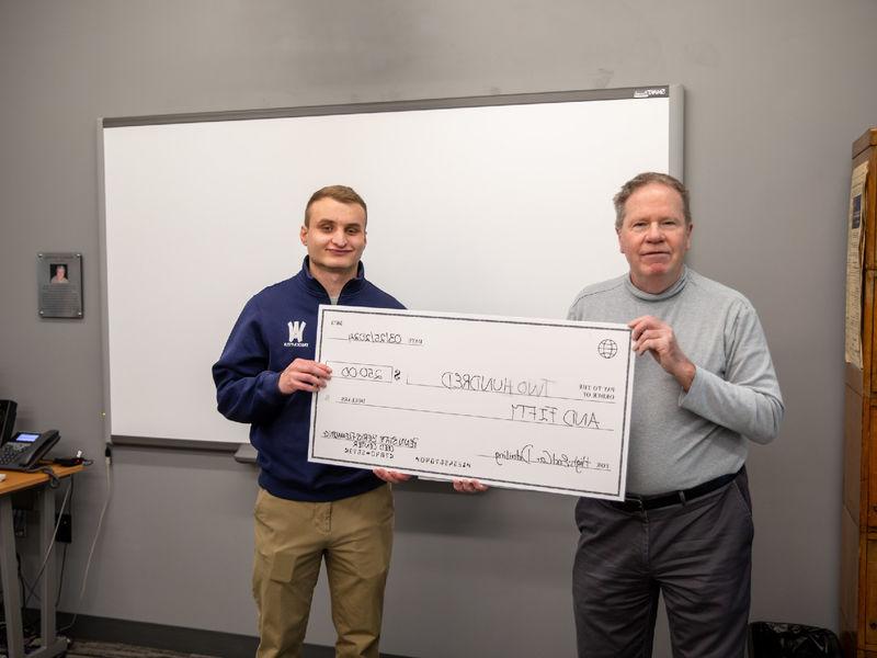 Male student holds check of $250 for photo