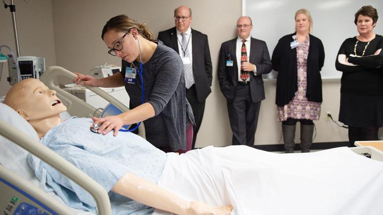 一名护士靠在人体模型上演示一项医疗技术